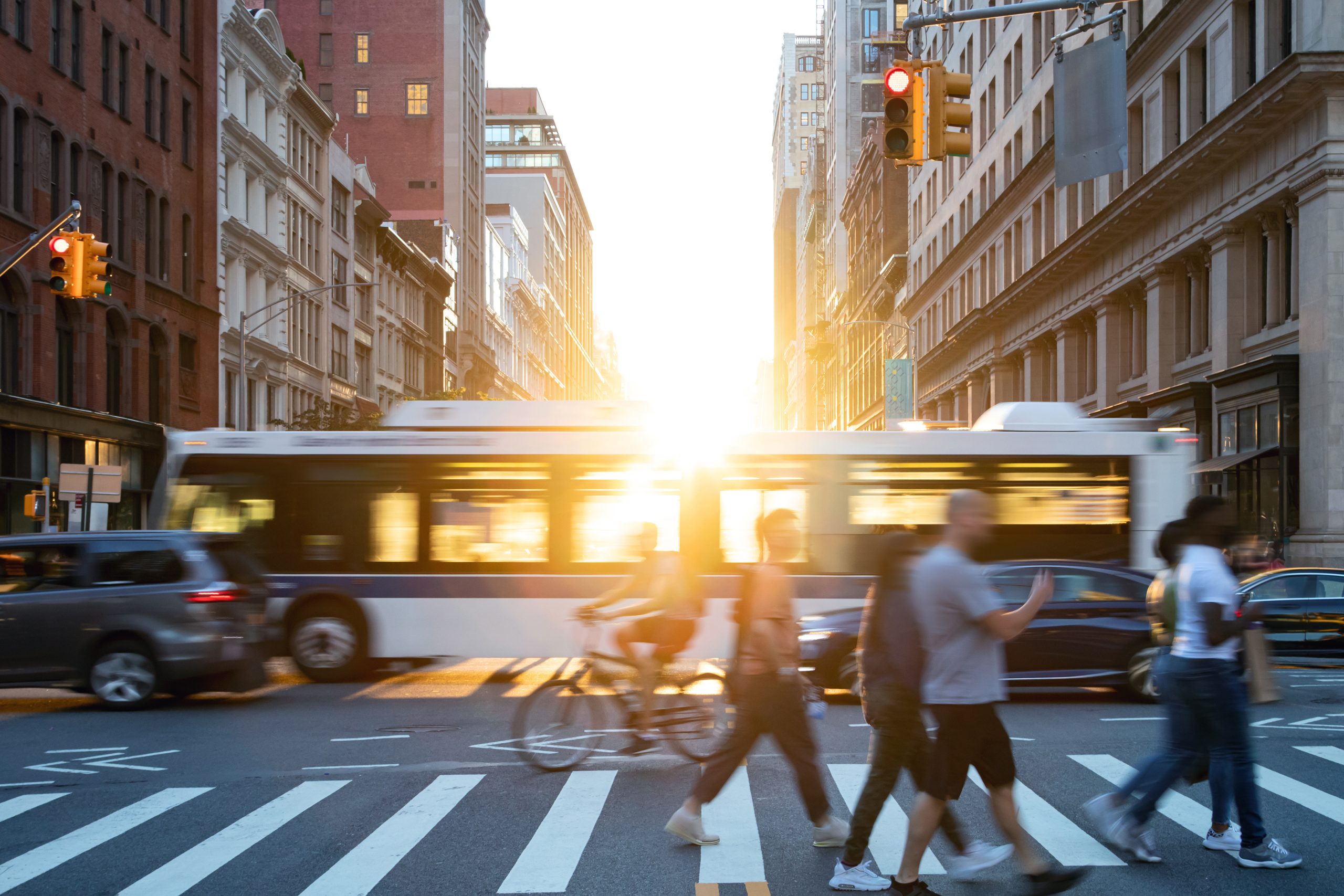 People, cars, bikes and buses traveling through a busy intersect